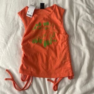 Urban sinched tank in orange size small with green frog and text. Never worn